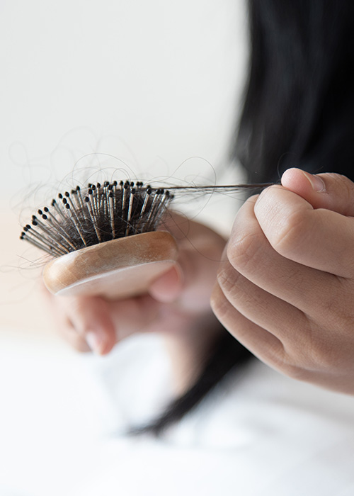Frau zupft ausgefallenes Haar aus Bürste