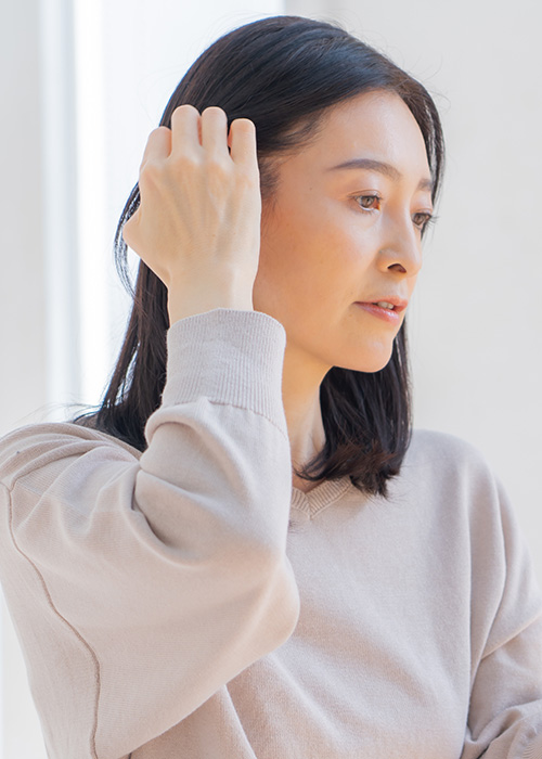 Frau streicht sich mit sorgenvoller Miene das Haar zurück