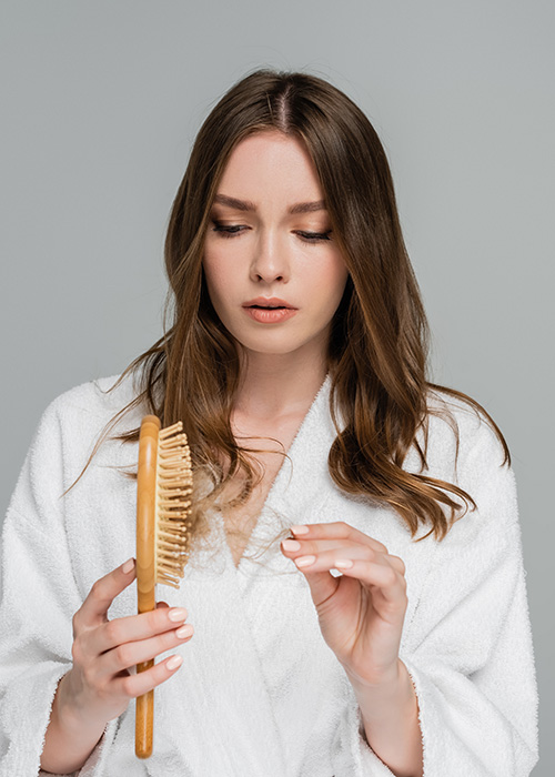 Frau bemerkt Haarausfall an ihrer vollen Bürste